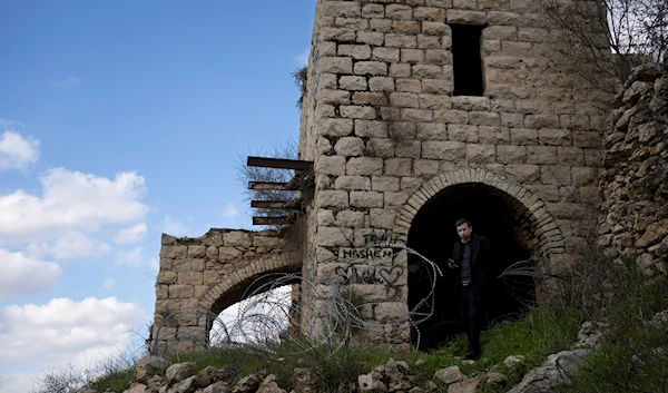 An Israeli settler stands beside a stolen Palestinian home in the village of Lifta, whose residents were forced out in 1948 during the Nakba, on the outskirts of Al-Quds, Sunday, Feb. 5, 2023. (AP)