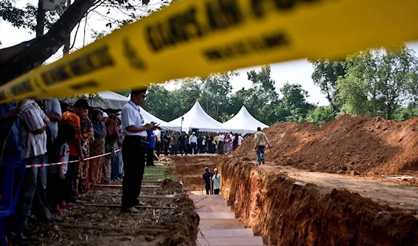 A Malaysian Muslim man stands near a pit during the re-burial of remains believed to be those of ethnic Rohingya found at human-trafficking camps in the country’s north, at Kampung Tualang, on June 22. (AFP)