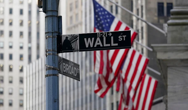 The Wall St. street sign is framed by the American flags flying outside the New York Stock exchange, Friday, Jan. 14, 2022, in the Financial District. (AP)