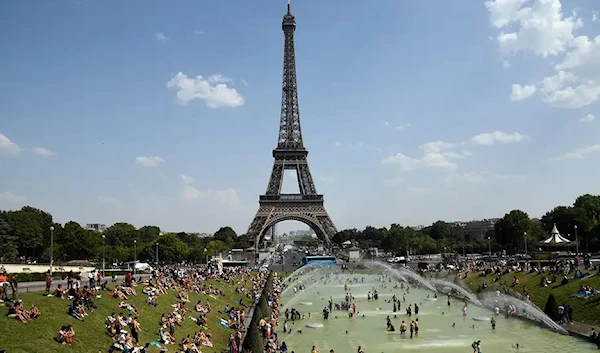 People cool off by the Trocadero Fountains next to the Eiffel Tower in Paris, on July 25, 2019, as a new heat wave hits the French capital (AFP)