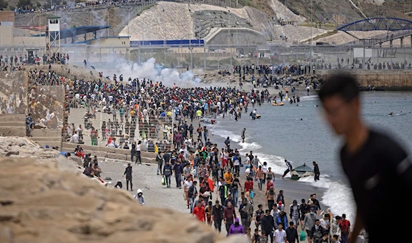 Spanish police try to disperse migrants at the border between Morocco and the Spanish enclave of Ceuta on May 18, 2021, in Fnideq (AFP)