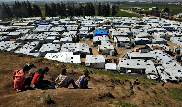 Displaced Syrian children slide down a hill, above a refugee camp in the town of Bar Elias, in Lebanon's Bekaa Valley, March 12, 2019. (AP)