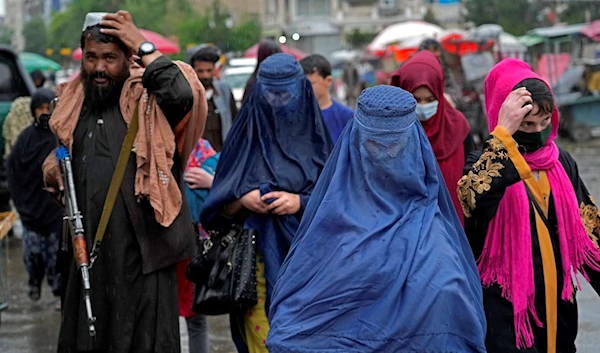 Afghan women walk through the old market as a Taliban fighter stands guard, in downtown Kabul, Afghanistan, May 3, 2022. (AP)