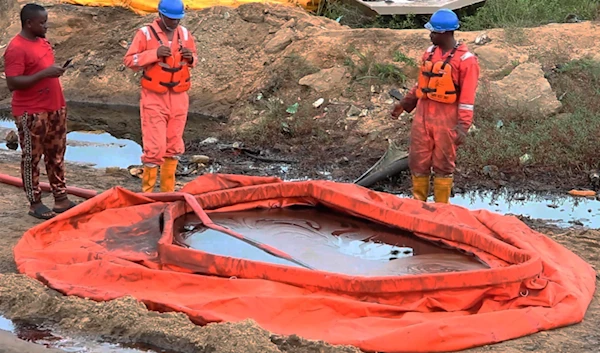 In this grab taken from video, workers stand by a container to collect oil spill waste, in Ogoniland, Nigeria, June 16, 2023. (AP)