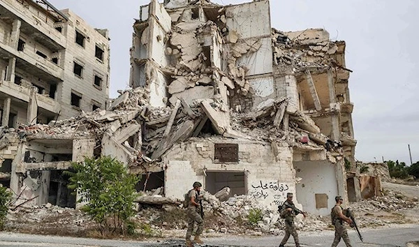 Soldiers patrol along a road past destroyed buildings atop the Arbaeen hill overlooking Ariha in the southern countryside of Syria’s Idlib province. (AFP)