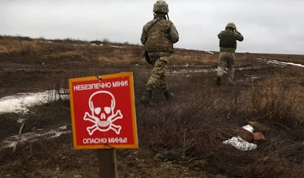 Ukrainian Military Forces servicemen walk past a metal plate which reads as 'Caution mines' near Luganske village, in Donetsk region, Jan. 11, 2022. (AFP)