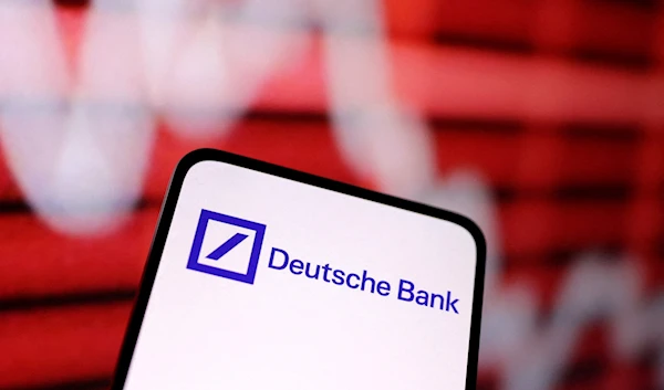 A logo of Deutsche Bank displayed on a phone screen in front of a declining stock graph, March 12 2023. (Reuters)