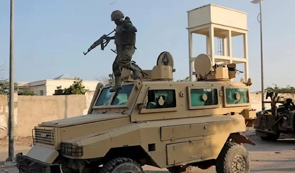 A soldier serving in the African Union Mission in Somalia jumps off a military vehicle near the scene of a suicide explosion in Mogadishu, Somalia, November 11, 2021. (Reuters)