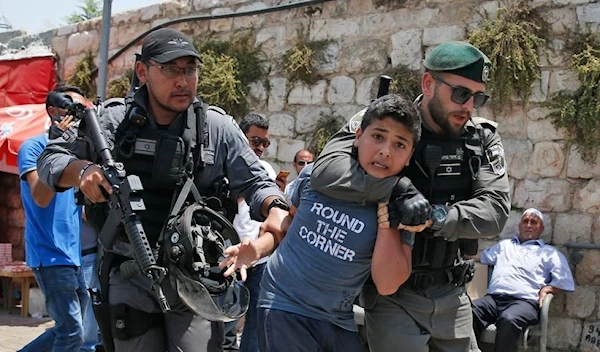 Israeli occupation forces detain a Palestinian child near Al-Aqsa Mosque, occupied Al-Quds, Palestine, July 17 2017. (AFP)