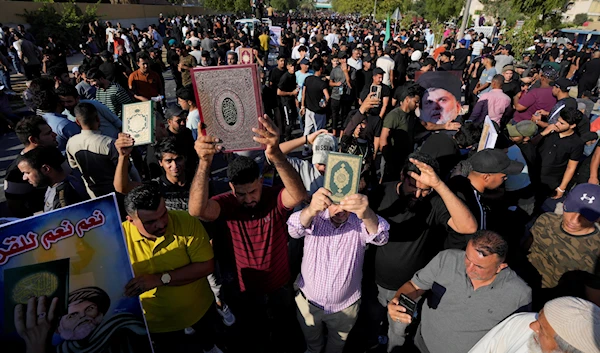 Supporters Iraqis holding up the Holy Quran in front of the Swedish embassy in Baghdad in response to the burning the holy book in Sweden, Baghdad, Iraq, June 30, 2023 (AP)