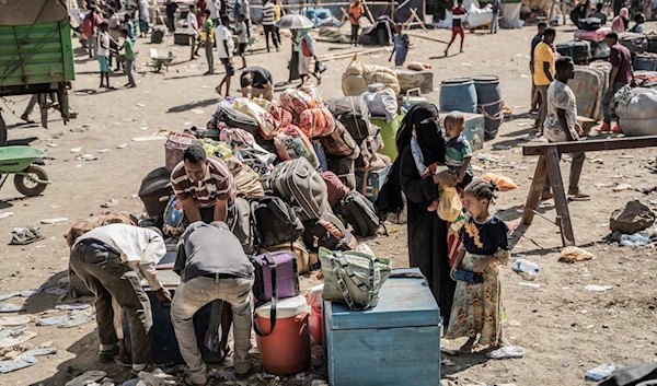 Refugees who crossed from Sudan to Ethiopia put their belongings on the ground for a security check in Metema. (AFP)