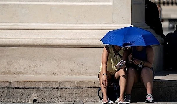 People use an umbrella to shelter from the sun near the Louvre Pyramid (Pyramide du Louvre) during a heatwave in Paris on June 26, 2019. (AFP)