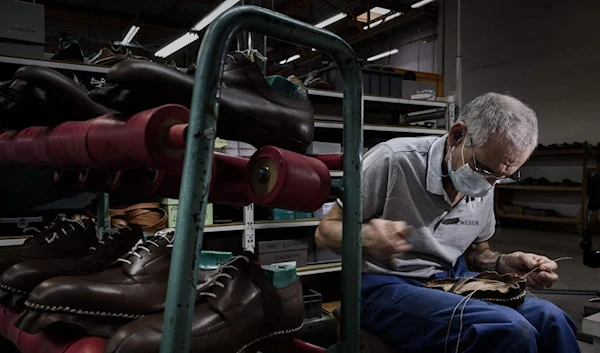 French shoemaker Weston's employee sews a shoe at the firm's factory in Limoges, on January 10, 2023 where all shoes are produced using traditional shoe-making techniques. (AFP)