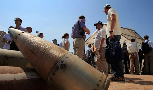 Activists and international delegations stand next to cluster bomb units (AP)