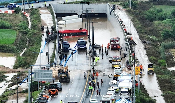 Rescuers work to search for survivors along a road submerged by floodwaters. (AP)