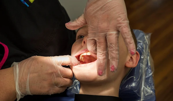 Stephanie Ableitner, a volunteer dental hygienist, performs a screening on Devin Teague, 11, of Bentonville, Ark., seen at Colgate and Champions for Kids for SIMPLE Giving, on Thursday, March 27, 2014, in Bentonville, Ark.