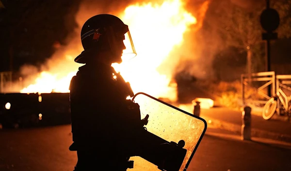 A firefighter looks on as vehicles set ablaze by protestors angered by the murder of 17 year old Nahel M. by 2 French Police officers in Nanterre, west of Paris, France, June 28 2023. (AFP)