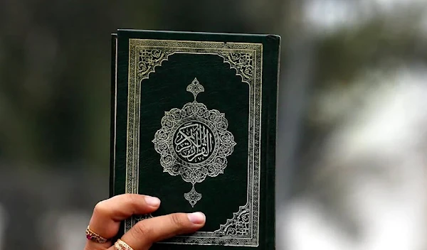 A man carrying the holy Quran during a protest (AP)