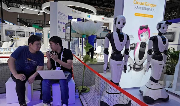 Workers chat near robots from Chinese intelligent robot manufacturer Dataa Robotics displayed during the 2023 World Artificial Intelligence Conference held in Shanghai, Thursday, July 6, 2023 (AP Photo/Ng Han Guan)