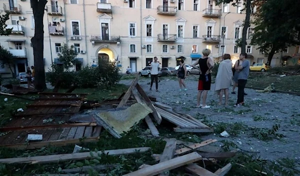 People stand among the debris outside a residential building after a missile strike in Odesa early in the morning of July 23, 2023 (AFP)