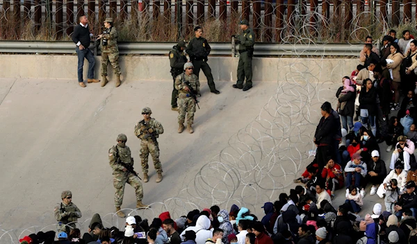 Migrants congregate on the banks of the Rio Grande at the U.S. border with Mexico, Dec. 20, 2022, where members of the Texas National Guard cordoned off a gap in the US border wall. (AP)