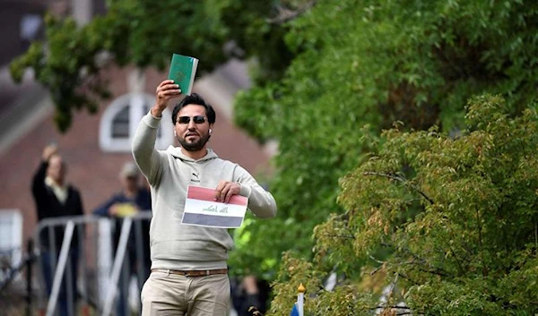 Iraqi refugee Salwan Momika holds up the Muslim holy book and a sheet of paper showing the flag of Iraq during a protest outside the Iraqi Embassy in Stockholm, Sweden, on July 20, 2023. (AFP)