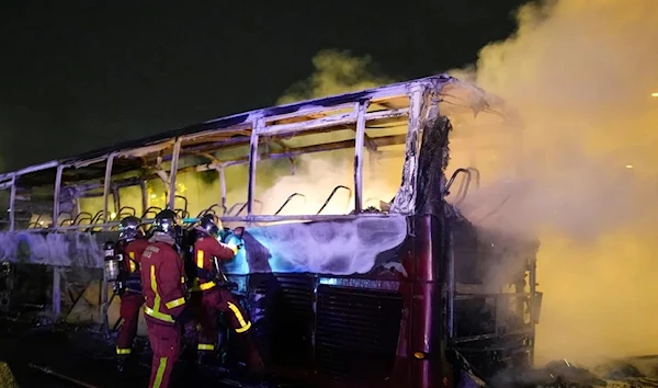 Firefighters use a water hose on a burnt bus in Nanterre, outside Paris, France. (AP)