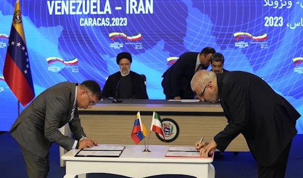 With Iranian and Venezuelan Presidents sitting in the background, the oil ministers of Venezuela's Pedro Tellechea and Iran's Javad Owji sign a deal in Caracas, Venezuela, on June 12, 2023. (AP)