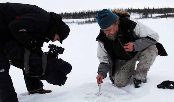 In this photo taken Oct. 23, 2010 Russian scientist Sergey Zimov demonstrates for AP Television News the emission of methane trapped under the ice of a Siberian lake near the town of Chersky, Russia. (AP)