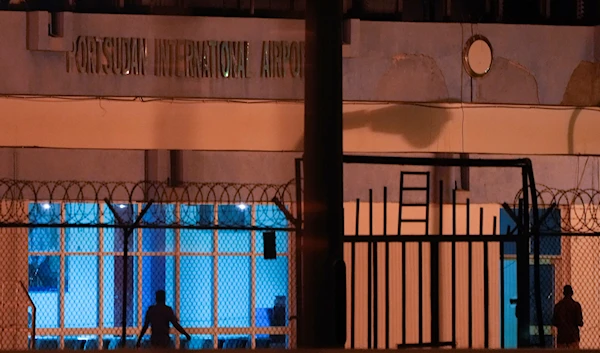 Sudanese evacuees wait under the gate of Port Sudan airport, Thursday, May 11, 2023 (AP)