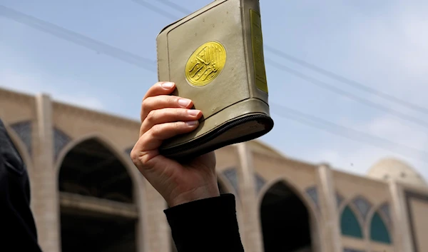 A worshipper holds a copy of the Quran Swedish-sanctioned Quran desecration demonstrations   Tehran, Iran, Friday, July 21, 2023 (AP)