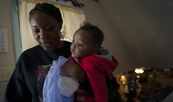 Ansonia Lyons carries her son, Adrien Lyons, as she takes him for a diaper change in Birmingham, Ala., on Saturday, Feb. 5, 2022. (AP)