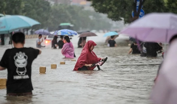 People wade through floodwaters along a street following heavy rains in Zhengzhou, in China’s central Henan province, on July 20. (AFP)