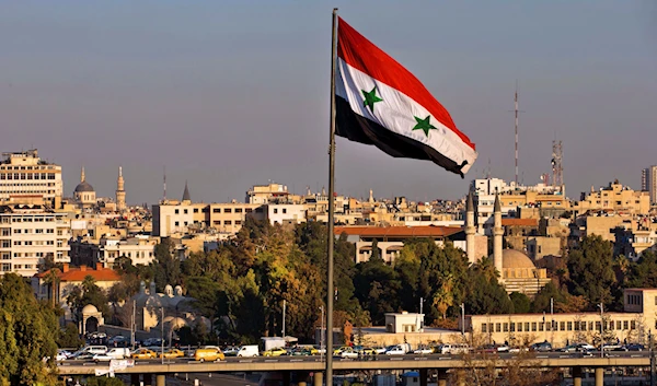 A Syrian national flag waves as vehicles move slowly on a bridge during rush hour, in Damascus, Syria, on Feb. 28, 2016. (AP)