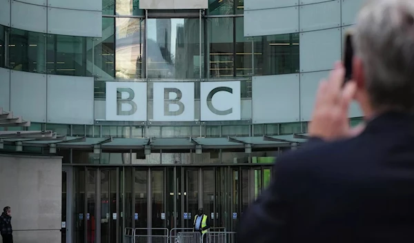 A man taking a photo of the BBC Headquarters in London, UK in October 2022 (AP)