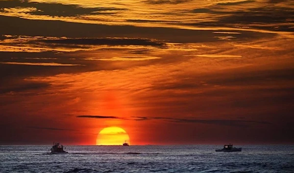 The sun rises over fishing boats in the Atlantic Ocean, September 8, 2022(AP)