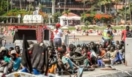 Migrants rest on the pier after disembarking from a 'cayuco' (wooden boat) following a rescue operation on July 4, (AFP)