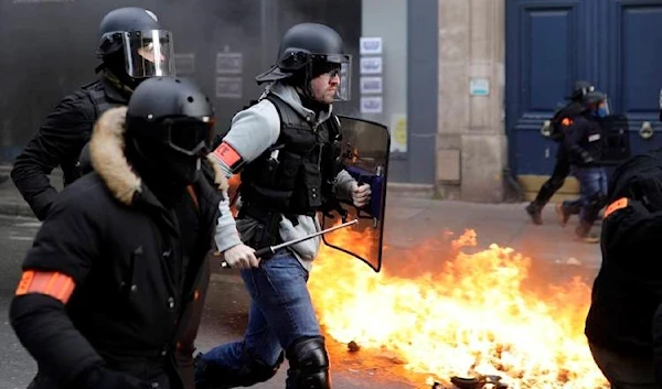 Riot police run past burning dustbins set in Paris on Saturday, February 9 2019 (AP)