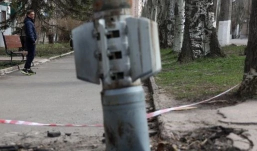 A man walks past an unexploded tail section of a 300mm rocket which appear to contained cluster bombs, Lugansk region on April 11, 2022 (AFP)