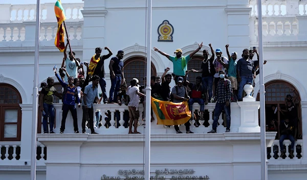 Sri Lankan protesters, some carrying national flags, stand on top of prime minister Ranil Wickremesinghe's office in Colombo, Sri Lanka, July 13, 2022 (AP)