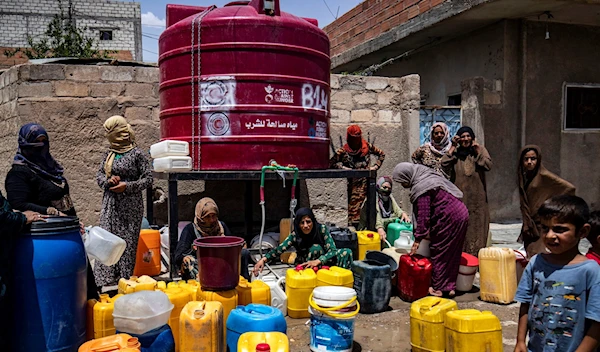 Syrian residents fill plastic jugs with water at a neighborhood water tank in Syria's northeastern city of Al-Hasakah on June 11, 2023. (AFP)