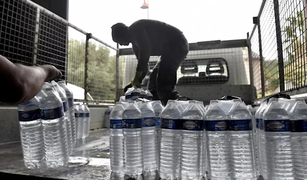 Municipal employees load packages of drinking water to be delivered to the residents of Corbere-les-Cabanes, southwestern France (AFP)