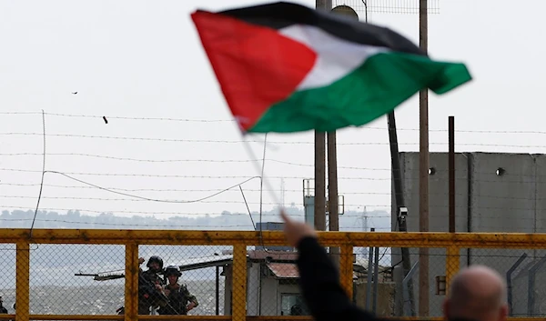 A Palestinian protestor waves his Palestinian flag infront of Israeli Occupationa Ofer prison near Betunia in the Israeli occupied West Bank, March 30, 2016. (AFP)