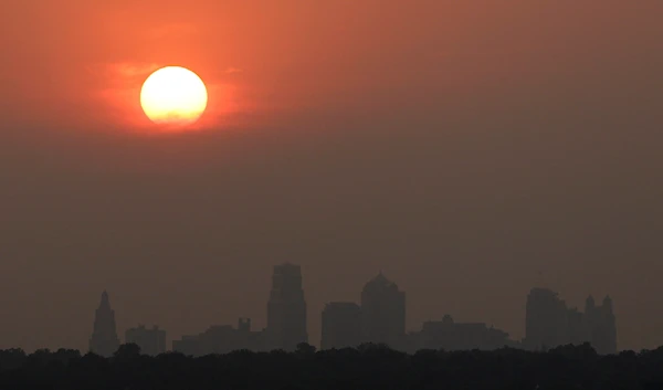 The setting sun is shrouded in hazy clouds as it sets beyond downtown Kansas City, Monday, June 13, 2011 (AP)