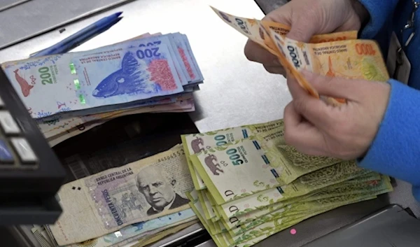 In this photo taken on August 15, 2019 a cashier counts Argentine pesos bills at a supermarket in Buenos Aires. (AFP)