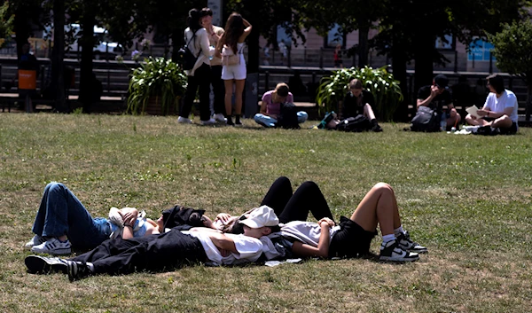 Germans rest in the Lustgarten park at the Museum Island in Berlin, Germany, Tuesday, July 18, 2023 (AP)