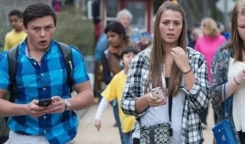 Three teens walk with their smartphones as they walk outside the Natural History Museum in Washington. (AFP via Getty Images)