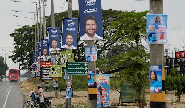 A man rides his motorcycle on a street with political propaganda of presidential candidate Jan Topic hanging from utility posts, in Babahoyo, Ecuador, Tuesday, Aug. 15, 2023. (AP)