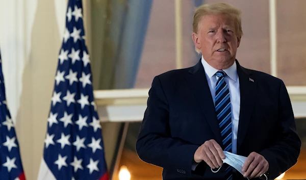 President Trump holds his face mask as he stands on the Blue Room Balcony at the White House in October 2020 (AP)