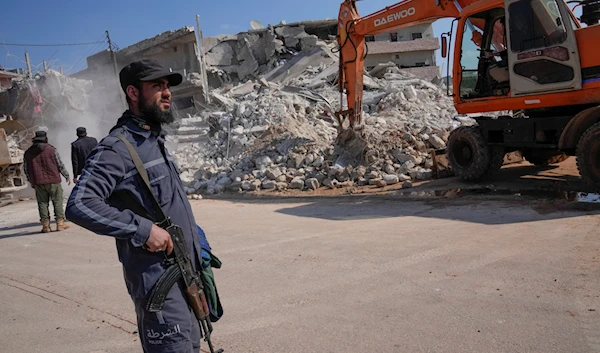 An Al-Qaeda-linked Hayat Tahrir Al-Sham terrorist stands in front of a destroyed house in Atareb, Syria, Feb. 12, 2023 (AP)